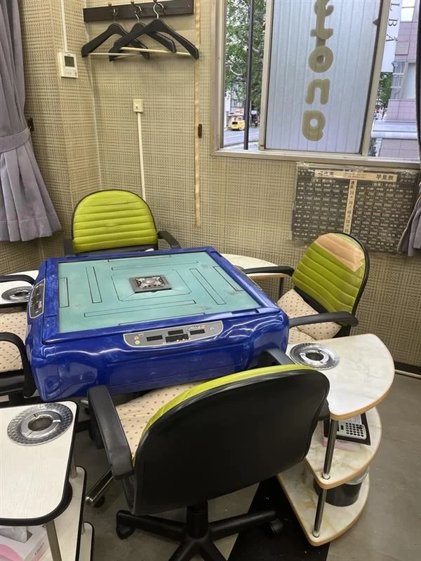 店内に並ぶ複数の全自動麻雀卓を横方向から見た写真